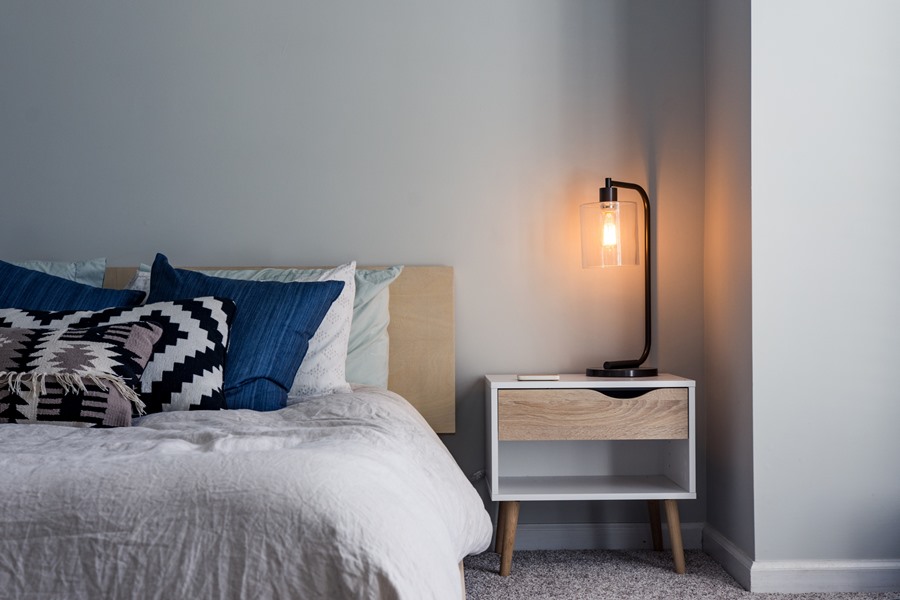 Modern hotel room, bed, wooden beside table and lamp