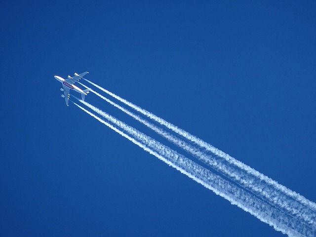 Buttom view of airplane with contrails in the dark blue sky